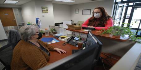 Female student standing behind a front desk speaking with front desk worker