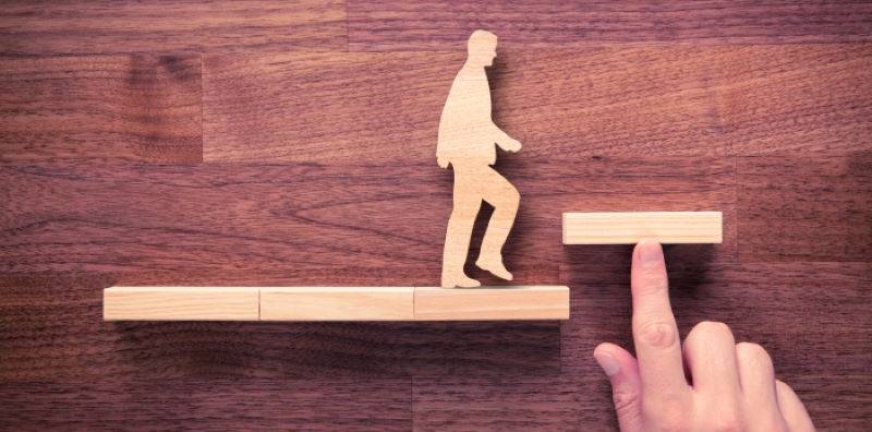 Wooden shelves with wooden cutout silhouette of a person walking up the shelves like steps