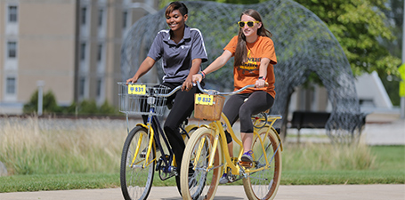 Two people riding bicycles next to each other.