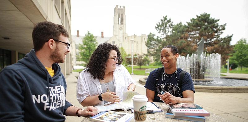 Students talking by the fountain in Student Union with University Hall in the background