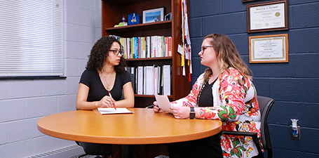 Student meeting with a staff member at a table in an office