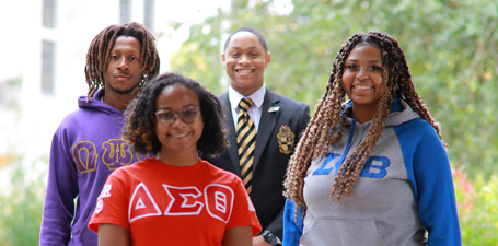 A small group of Greek students standing on campus.