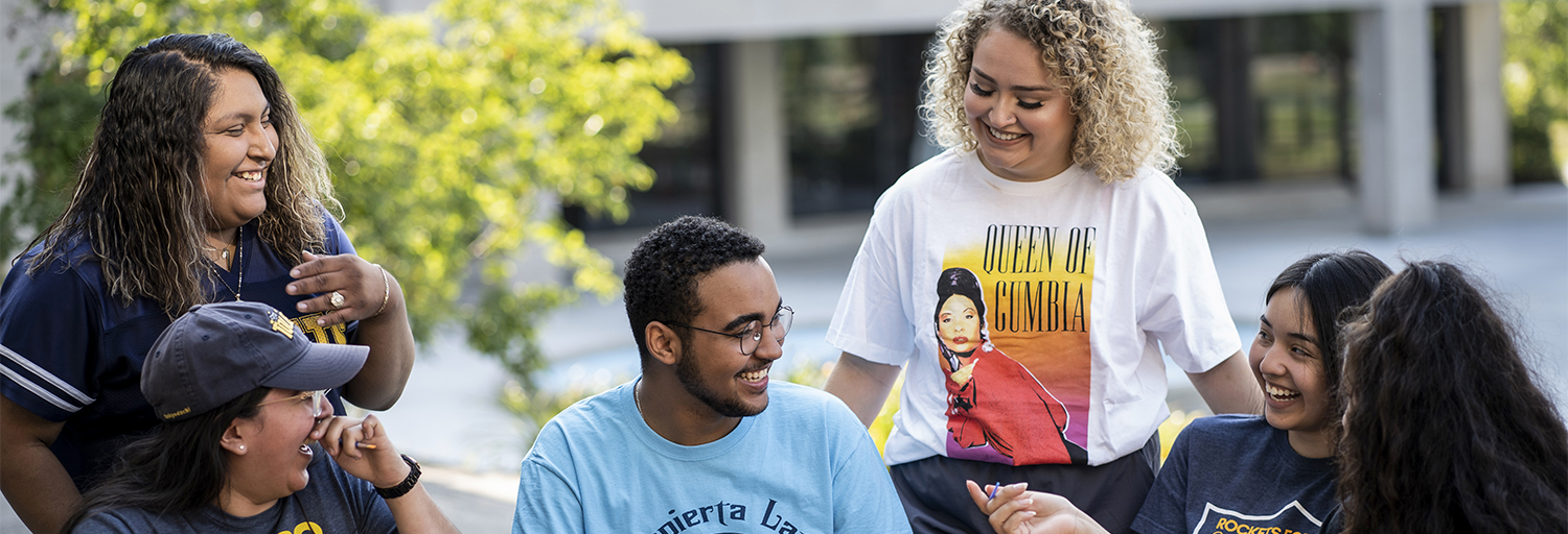 Hispanic students enjoying painting and laughing around a table