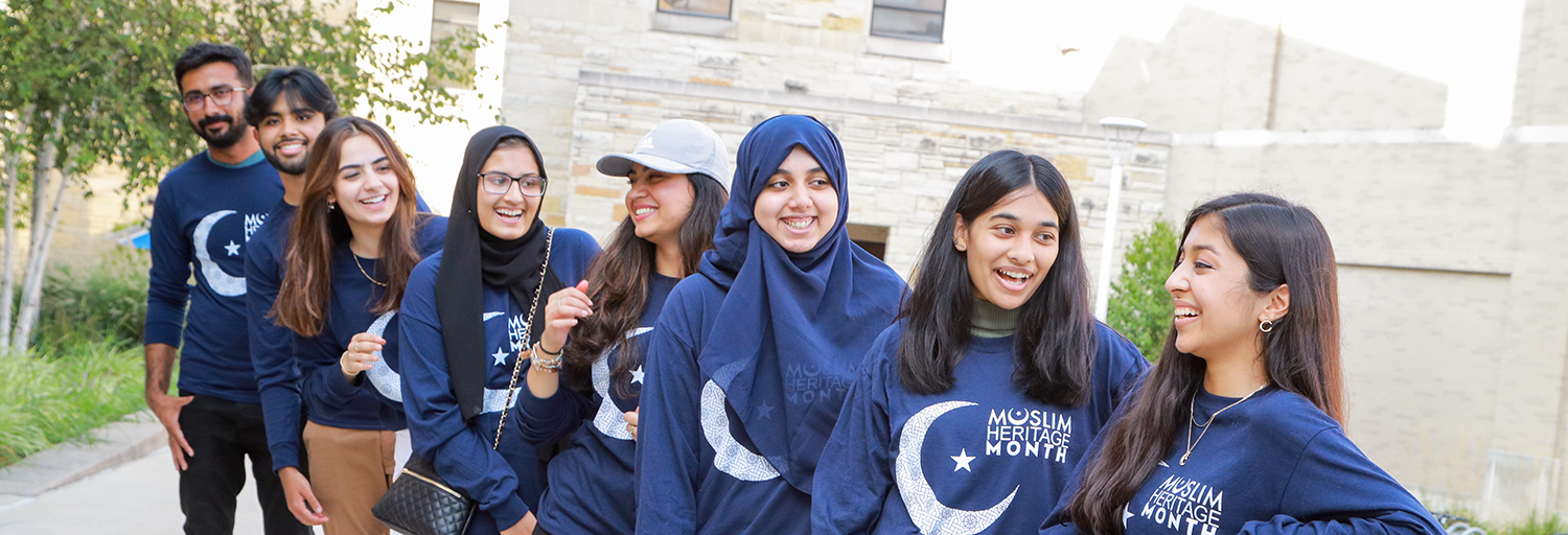 Muslim students standing in a line outside Carlson Library and chatting