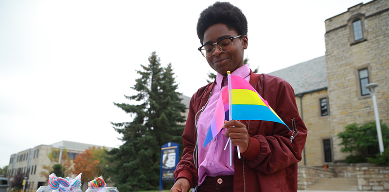 Student holding bisexual and pansexual flags