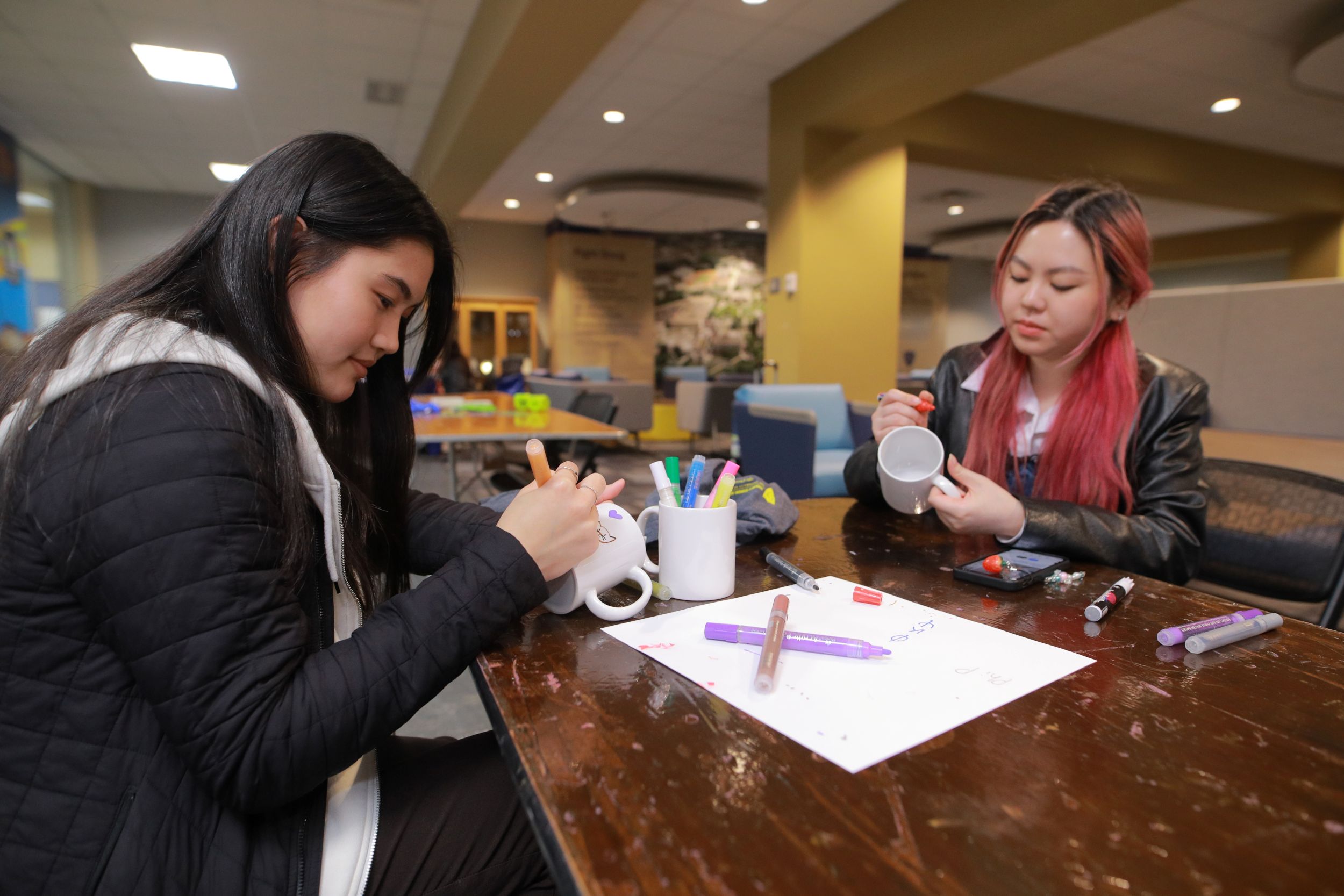 Two female students painting in the Trimble Lounge