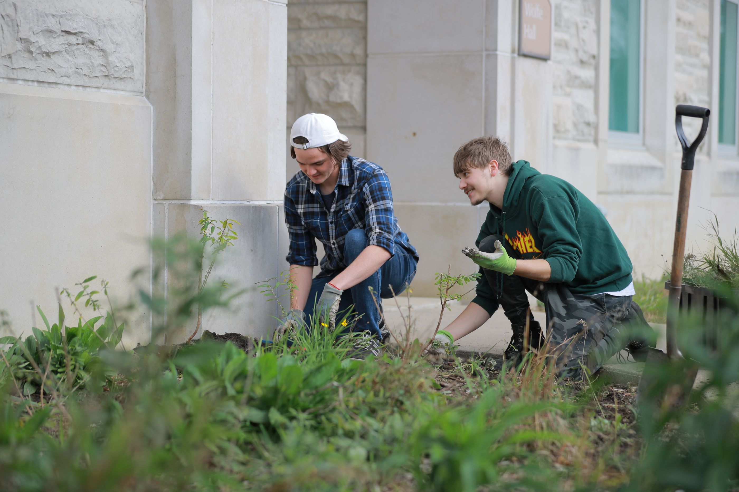 two utoledo students outside working in a flower bed
