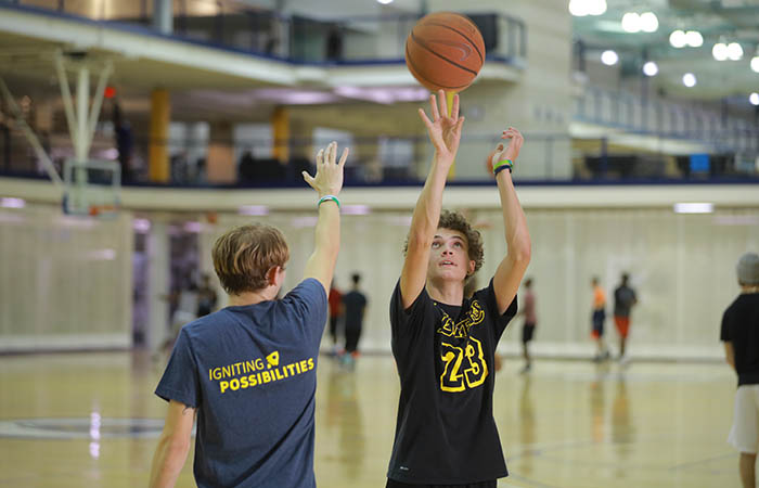 a young man shoots a basketball against a defender