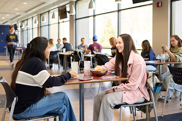 Students eating food in a dining area.