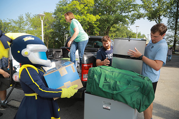 Students carrying their belonging for move-in, helped by mascot Rocksy.