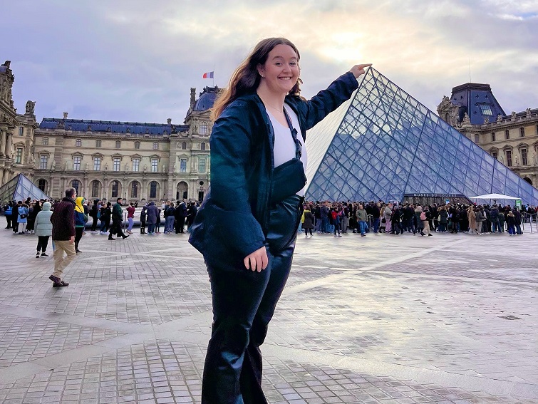 girl touching tip of Louvre pyramid