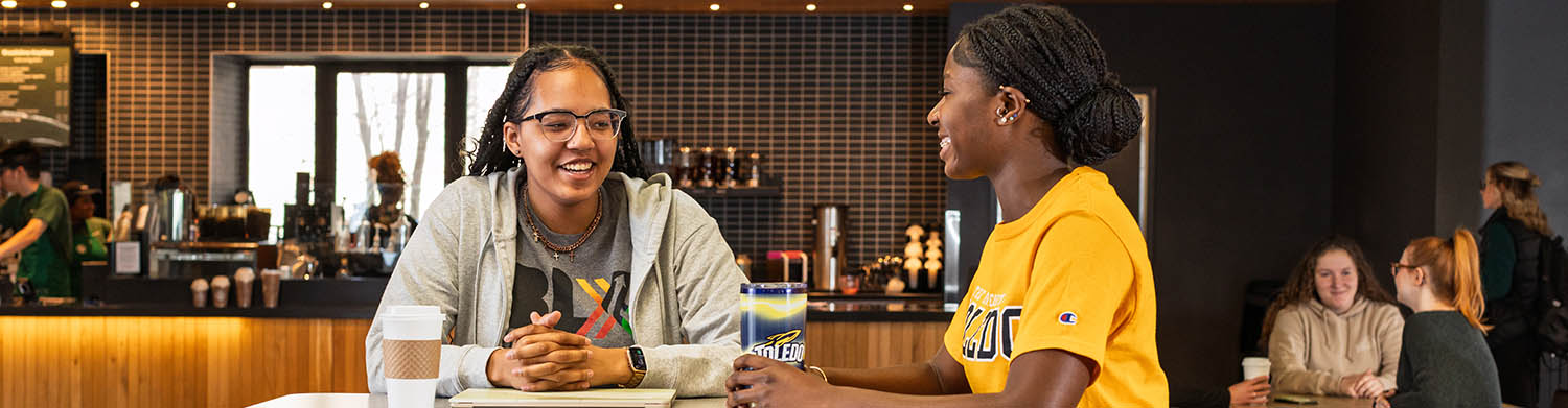 two students sitting at Starbucks in the UToledo library talking