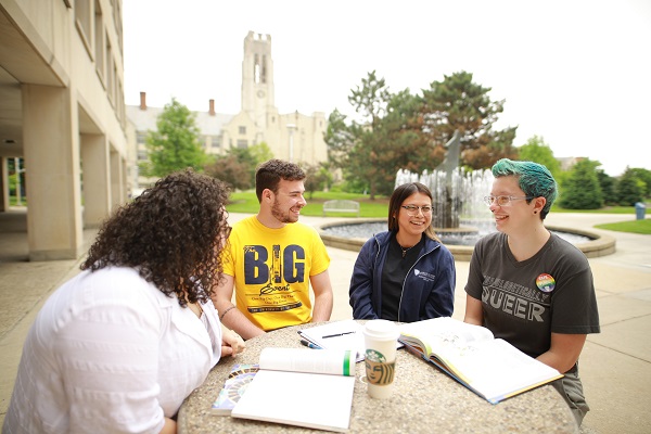 A group of students sitting around a table with books and drinks