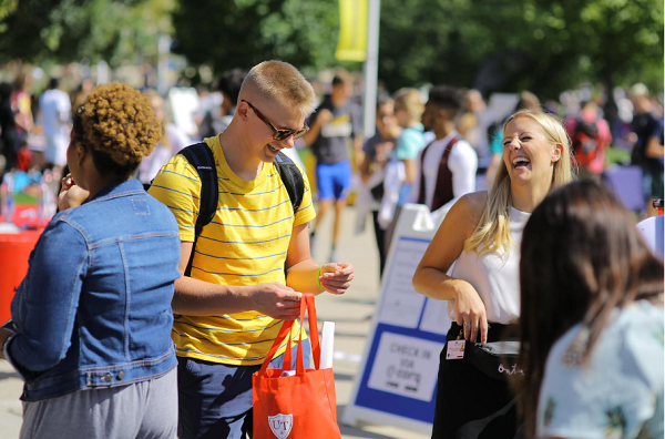 Students in a crowd smiling at an outdoor event