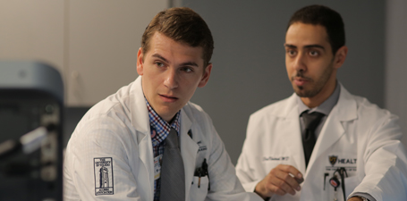 Two students practicing using medical equipment 