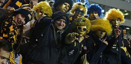 A group of Blue Crew, wearing gold face-covering masks and blue or gold wigs