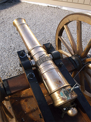 A metal cannon with the word Toledo molded on it, supported by wooden wheels