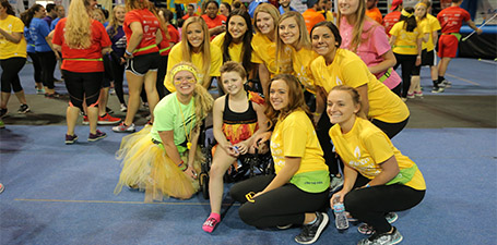 A group of students dressed in vibrant gold outfits huddling together for a photo